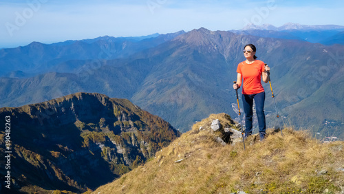 Woman hiker goes hiking, stands on top of mountain and looks at autumn nature mountains landscape in sunny weather. Outdoor activities. Copy space