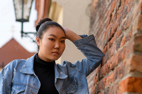 Young Mongolian woman wears urban fashion and standing by the brick wall.