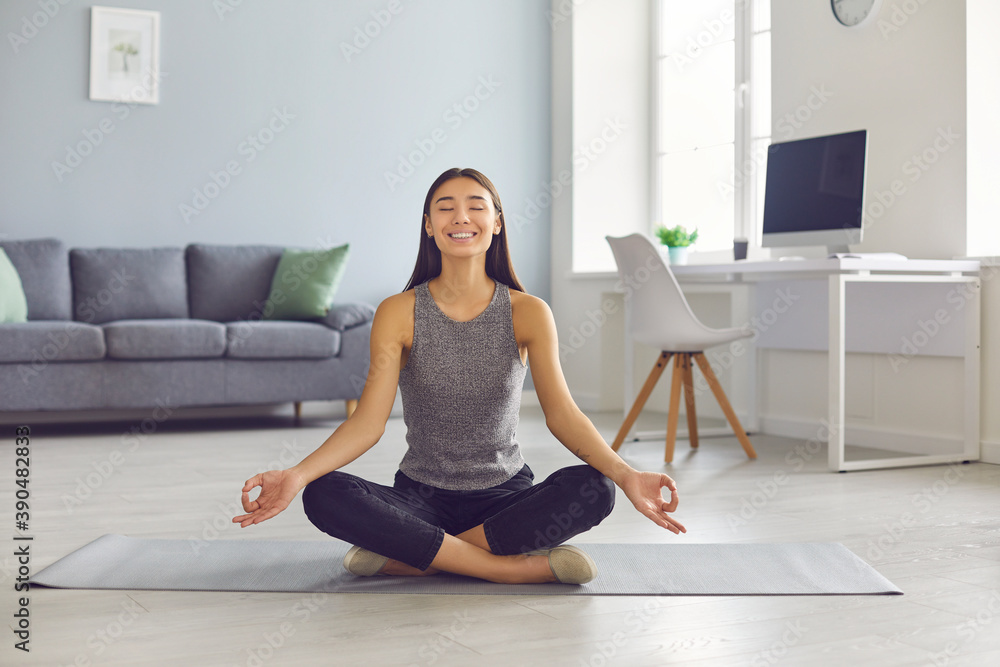 Happy young woman taking break from work in her home office and enjoying meditation in easy pose Happy young woman taking break from work in her home office and enjoying meditation in easy pose