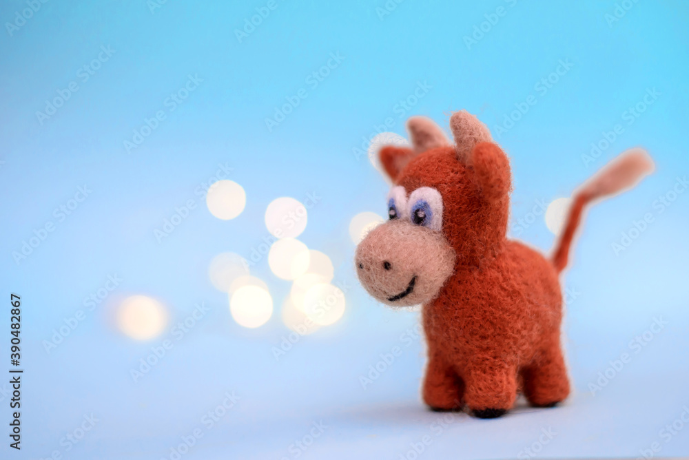 Fototapeta premium Felt toy bull on a blue background with bokeh
