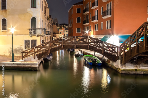 Fototapeta Naklejka Na Ścianę i Meble -  Night view of illuminated old architecture, floating boats and light reflections in canals water in Venice, Italy.