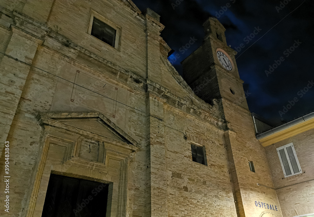 Facciata di una chiesa antica di notte con campanile luce della luna e nuvole in cielo