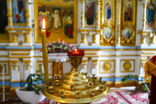 Lamp, candles in front of icons in the Orthodox Church. Burning wax candles, cross and icons in the monastery. Christianity. Altar in the church. The concept of the Orthodox faith.
