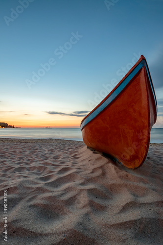 beauty morning with the lonely red boat on the sea beach. Vertical view