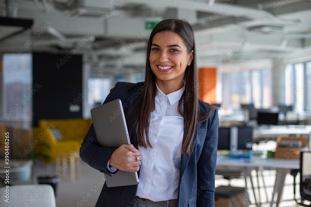 Fototapeta premium Portrait of the beautiful businesswoman holding a laptop in the office.