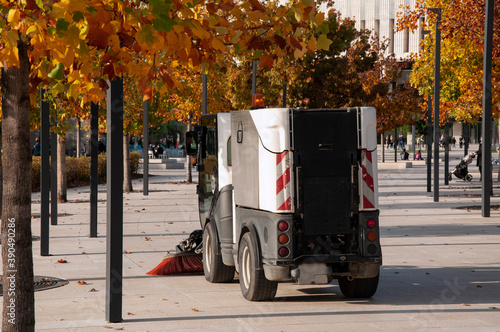 A swiper sweeps autumn leaves in a park square. photo