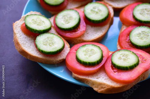 Sandwiches on a green plate with cucumber and tomato on white bread