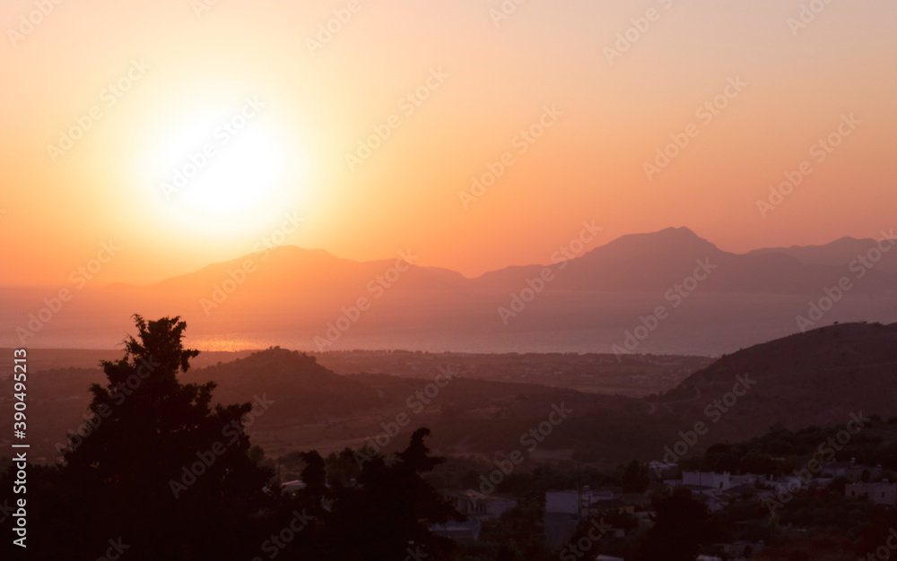 Sunset in the mountains. Layered landscape shot with the tip of the trees in the foreground