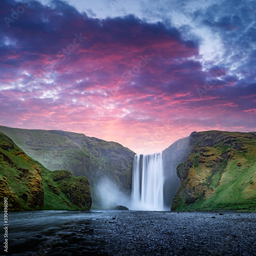 Famous Skogafoss waterfall on Skoga river in sunset time. Iceland  Europe. Great purple sky glowing on background. Landscape photography