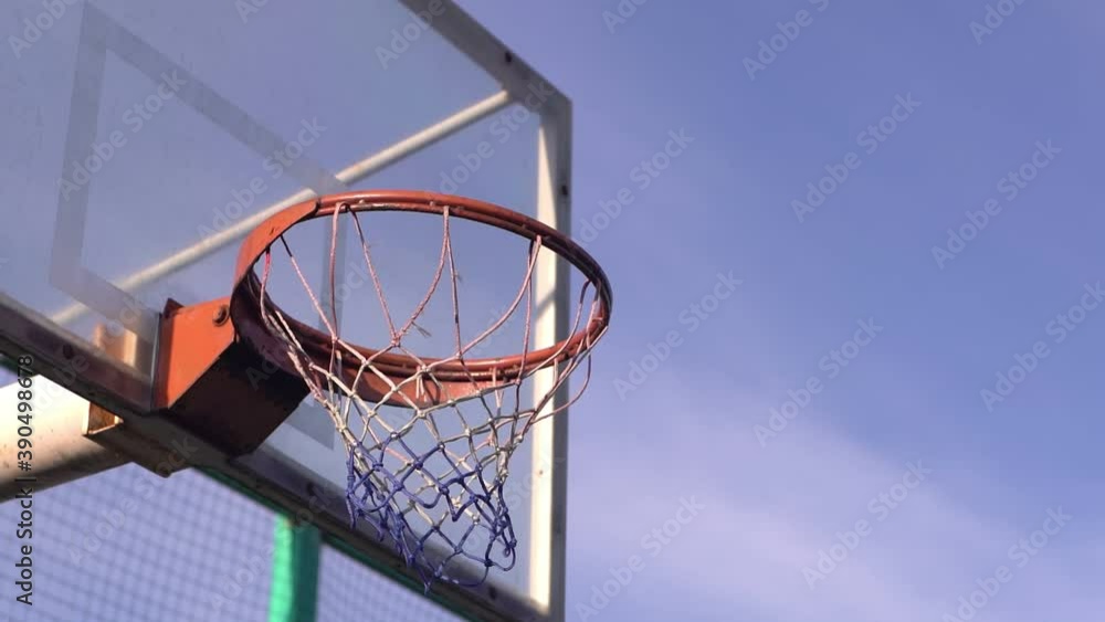 The ball flies into a basketball hoop against the background from clouds. The ball flies into a basketball hoop against the background from clouds.