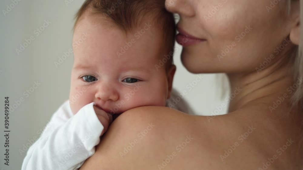 close-up of the face of a newborn baby, mom holds and kisses her close-up of the face of a newborn baby, mom holds and kisses her