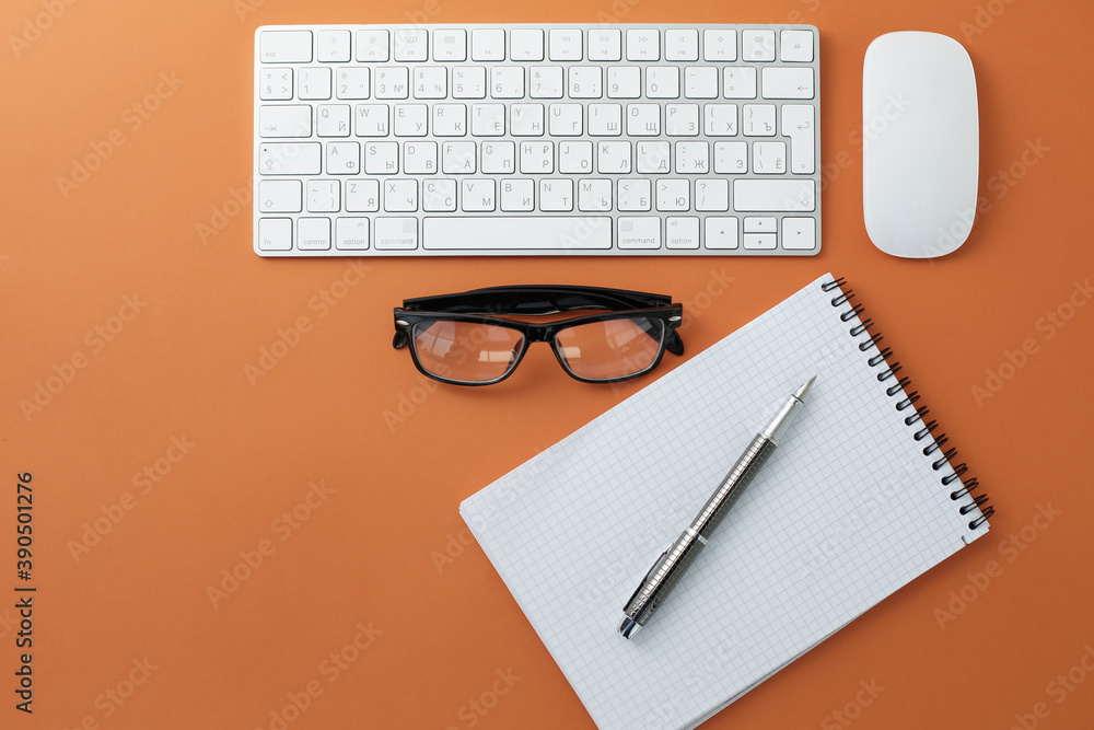 Glasses mouse keyboard notepad and pen on orange background Glasses mouse keyboard notepad and pen on orange background