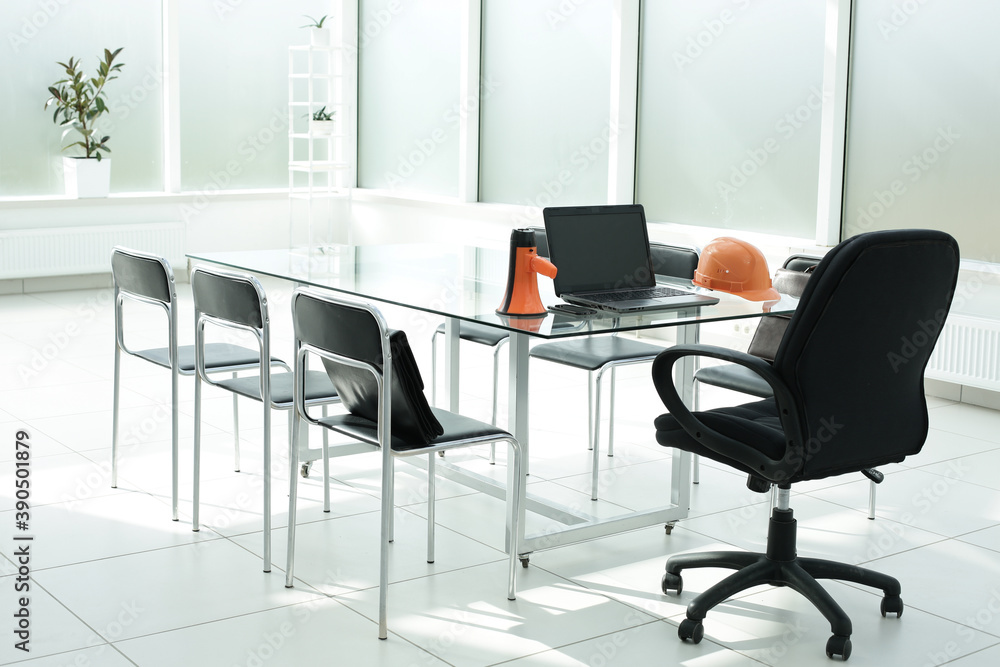 Laptop loudspeaker construction helmet on glass table in office space Laptop loudspeaker construction helmet on glass table in office space