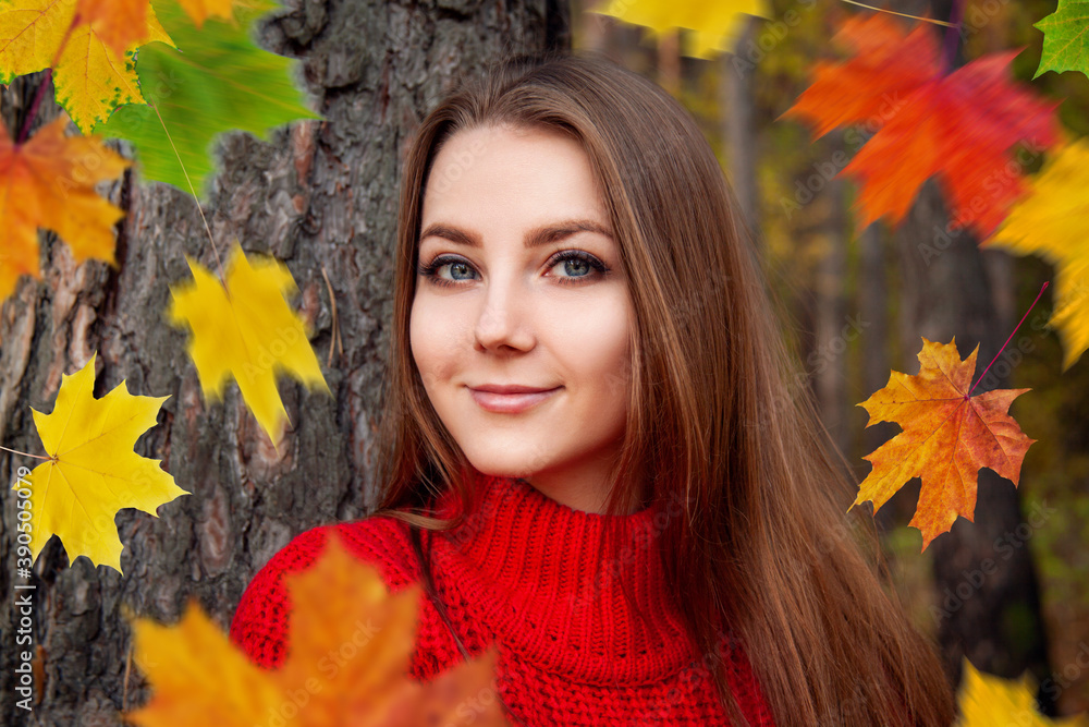 Young woman in red sweater on the autumn park background among falling maple leaves. Young woman in red sweater on the autumn park background among falling maple leaves.