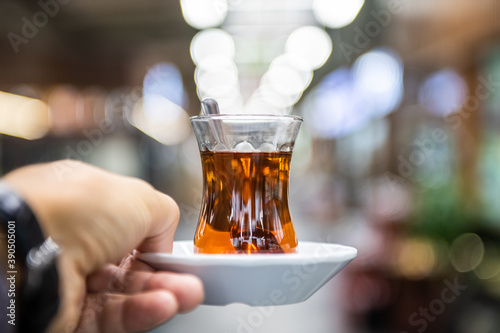 Man holding cup of turkish tea against blurred food court on background