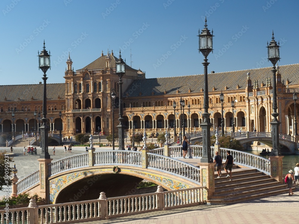 Bridge with tourists in Plaza de EspañaIlluminated windows in the arcades of Plaza de España