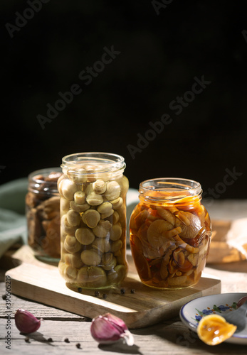Glass jar with canned mushrooms. Fermented food on a wooden table