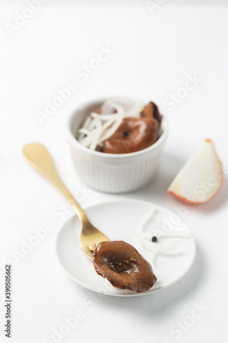 Ceramic bowls with canned mushrooms. Fermented food on a white plate with onion