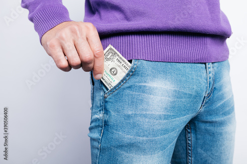 young guy in tight jeans takes out a banknote from his pocket. concept: investment, addiction to games and bad habits. man posing on a white background. unemployment benefits photo