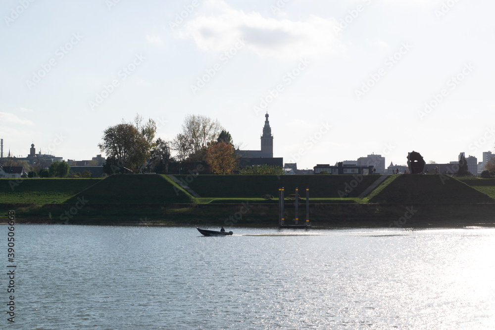 Fototapeta premium boat driving in front of the Skyline of the Dutch City of Nijmegen