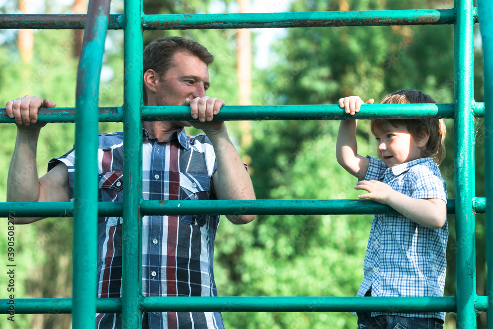 Obraz premium Father and his little son playing on the park playground.