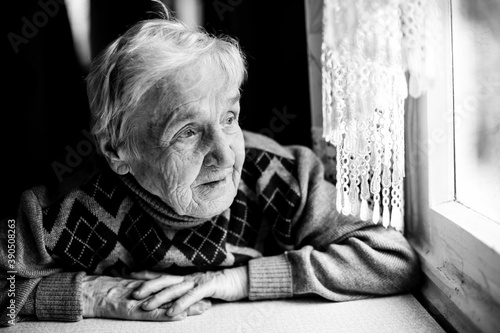 An old woman looking at the window. Black and white photo.