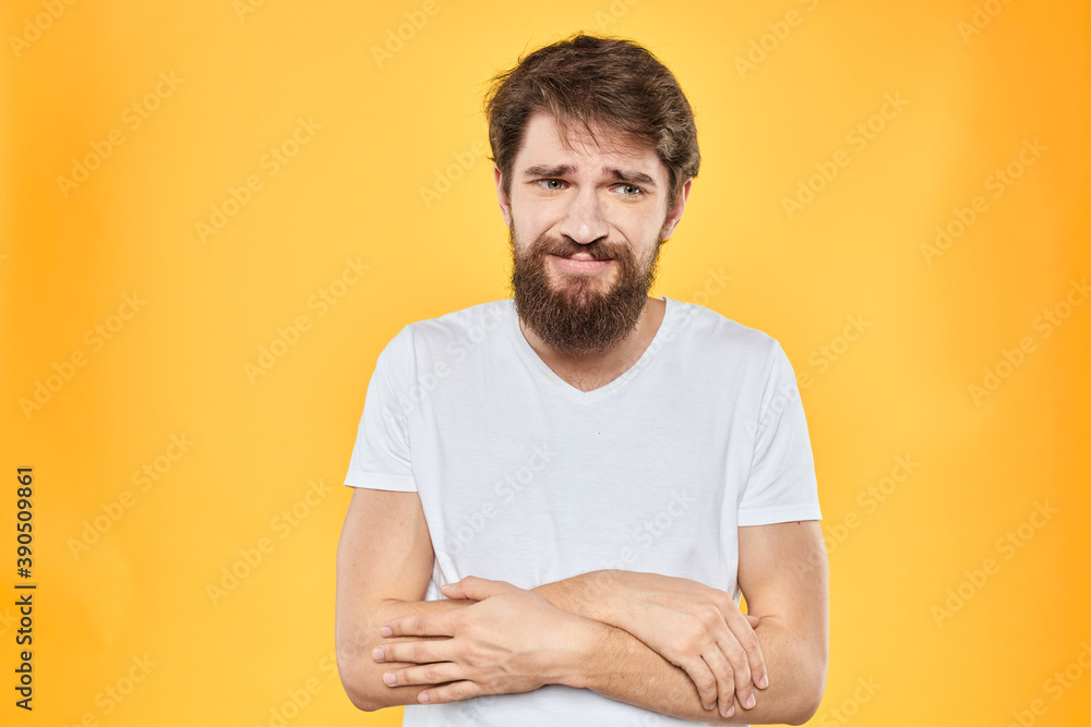A man in a white t-shirt gestures with his hands studio lifestyle yellow background emotions A man in a white t-shirt gestures with his hands studio lifestyle yellow background emotions