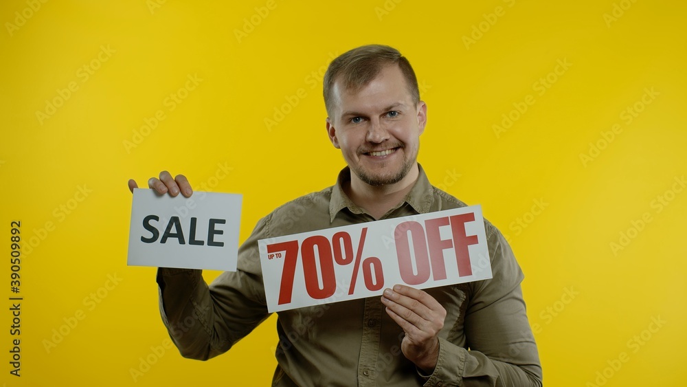 Great discounts. Happy joyful blonde man showing Sale word and showing Up To 70 percent Off purchase inscription. Shopping with low prices, Black Friday concept. Yellow background Great discounts. Happy joyful blonde man showing Sale word and showing Up To 70 percent Off purchase inscription. Shopping with low prices, Black Friday concept. Yellow background