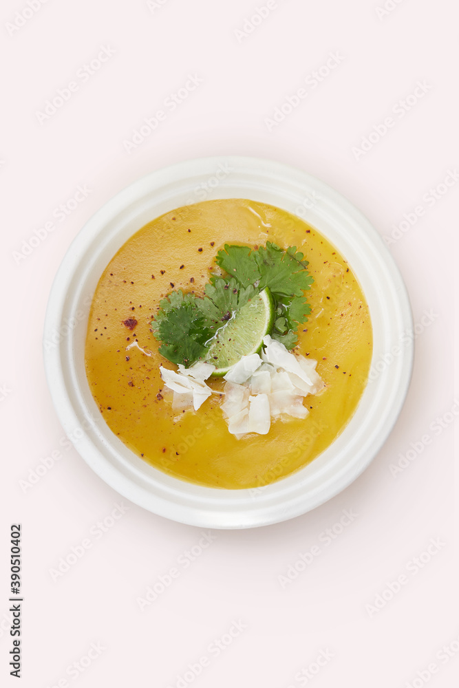Sopa de batata en bowl descartable biodegradable sobre fondo rosa con topping de lima, coco rallado, perejil y pimiento Sopa de batata en bowl descartable biodegradable sobre fondo rosa con topping de lima, coco rallado, perejil y pimiento