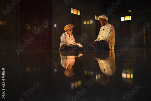 muslim boy sitting in mosque with islamic teacher learning koran book