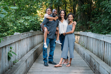 Portrait of happy mixed race family on bridge in nature park
