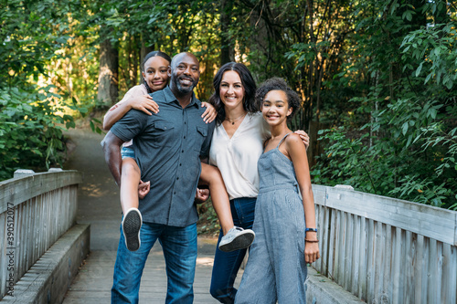 Portrait of happy mixed race family on bridge in nature park