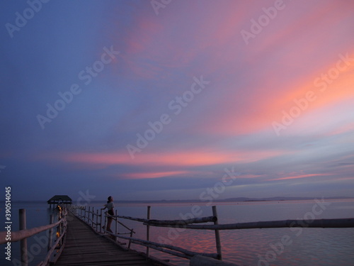 A woman stares at the beautiful reddish sky after sunset, Marine Sanctuary, Nalusuan Island, Cebu, Philippines