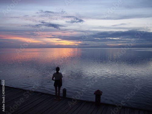 A woman stares at the beautiful reddish sky after sunset, Marine Sanctuary, Nalusuan Island, Cebu, Philippines
