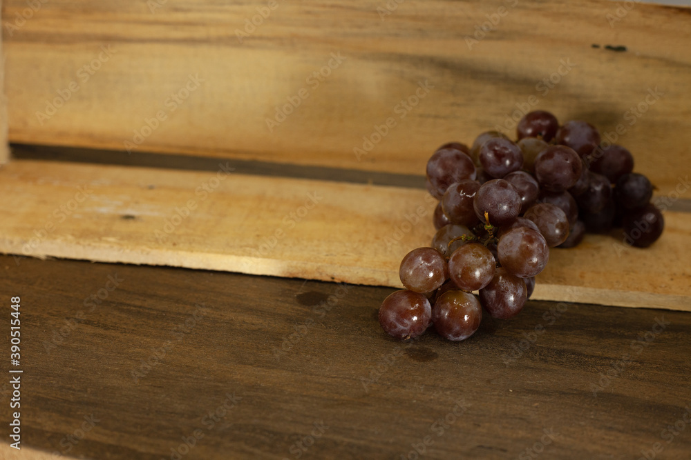 Champagne, purple, small grapes on top of wooden box. Space for art. Champagne, purple, small grapes on top of wooden box. Space for art.
