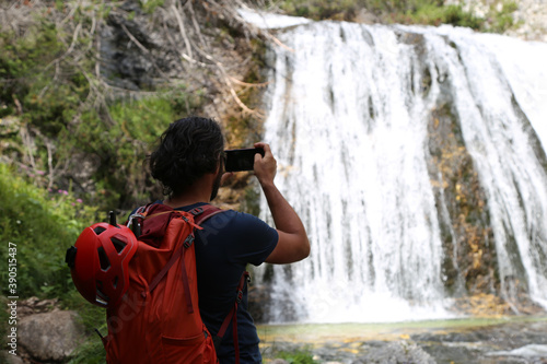 Man taking photo of waterfall with his phone