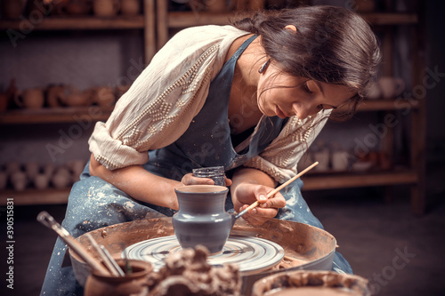 Charming handicraftsman creates a new pottery from clay on a potter's wheel. Pottery workshop.