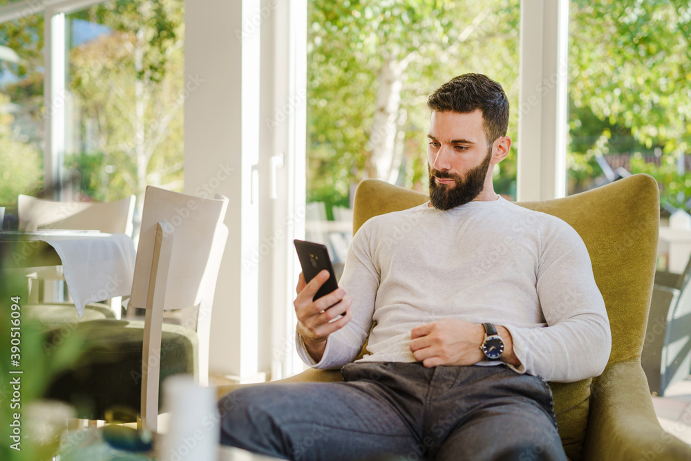 Portrait of adult good looking caucasian man sitting at cafe in day using mobile phone - Male with beard online date on internet while waiting sending love in video call - dating concept Portrait of adult good looking caucasian man sitting at cafe in day using mobile phone - Male with beard online date on internet while waiting sending love in video call - dating concept