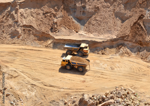 Mining trucks transports sand in an open pit. View of the quarry where sand is mined. Mining industry concept. Out of focus, possible granularity, motion blur photo