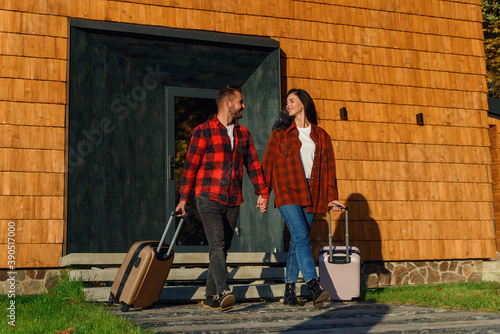 Young caucasian lovely couple with luggage leaving house for joint vacation. Happy family concept. © gorynvd