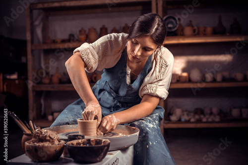 Charming craftsman works with clay on a potter's wheel. The concept of craft creativity. photo