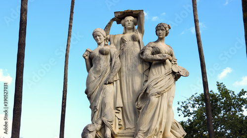 Cuadro en lienzo 3 statues of women representing the arts as muses with palm trees in the backgro