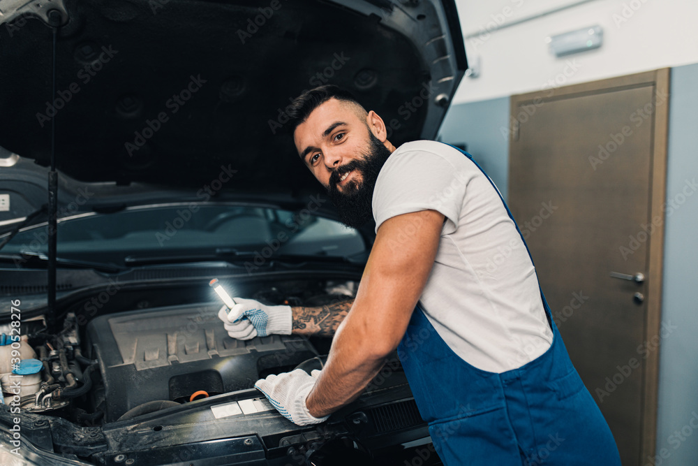 Car mechanic working at vehicle maintenance garage. He is doing periodic car condition check. Car mechanic working at vehicle maintenance garage. He is doing periodic car condition check.