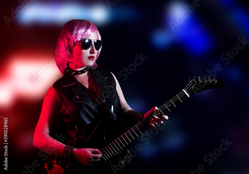 Young attractive pink haired rocker woman playing the electric guitar