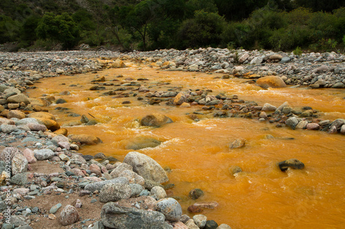 Yellow river called River of Gold due to the presence of iron in the water, flowing across the rocky valley, forest and mountains in La Rioja, Argentina. photo