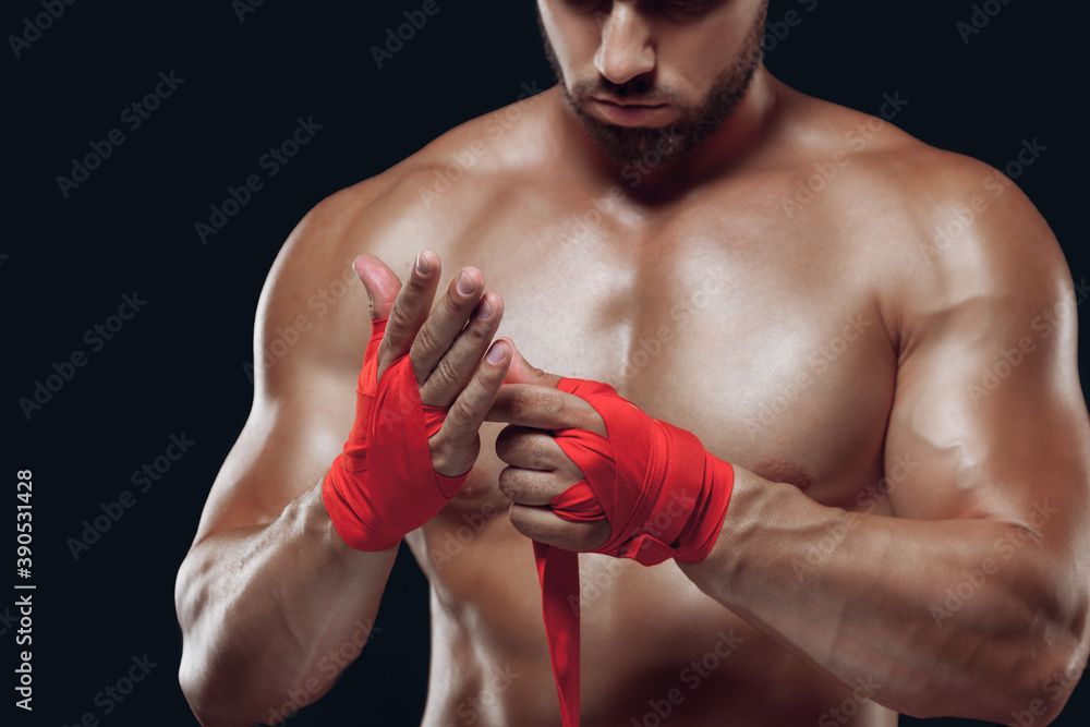 Close up portrait of fighter hands applying bondage tape on hands isolated on black background