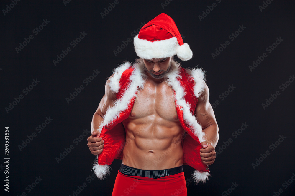 Sexy Santa Claus. Bodybuilder young handsome santa clause smile wearing Santa  Claus hat shows off abs cubes at New Years eve and Christmas winter holiday  black background. Stock Photo | Adobe Stock
