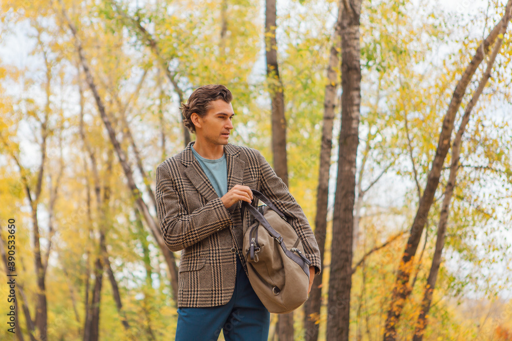 Tall handsome man with a bag on the autumn alley Tall handsome man with a bag on the autumn alley