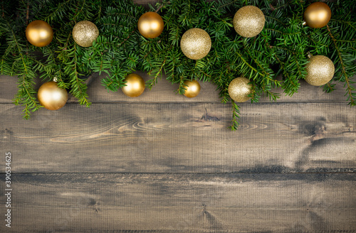 Christmas background with green branches and christmas balls on the rustic wooden background. Selective focus. Flat lay.
