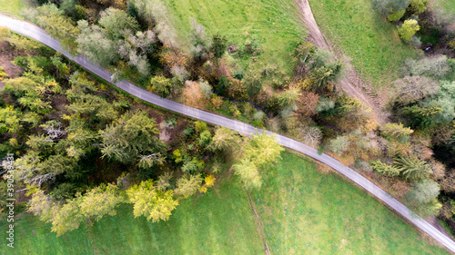 Obraz na płótnie Top view of road in forest and green fields w salonie